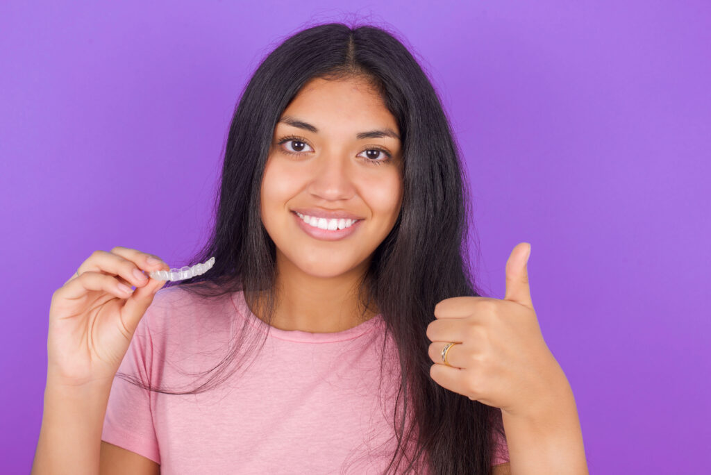 Hispanic teenage girl holding Invisalign clear aligners