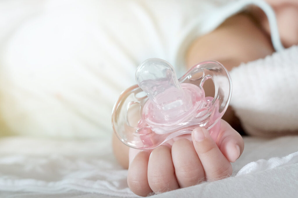 Close up of baby hands with pacifier. Focus is on baby hands