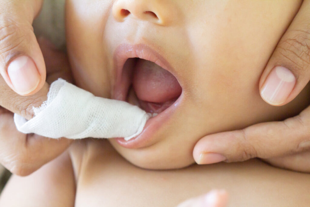 Mother cleans the teeth of a little boy, him to reduce pain from erupting , baby teethfingertip brush for children, Clean cloth fter bathing at home, Asian family, hygiene. Zoom Selective focus